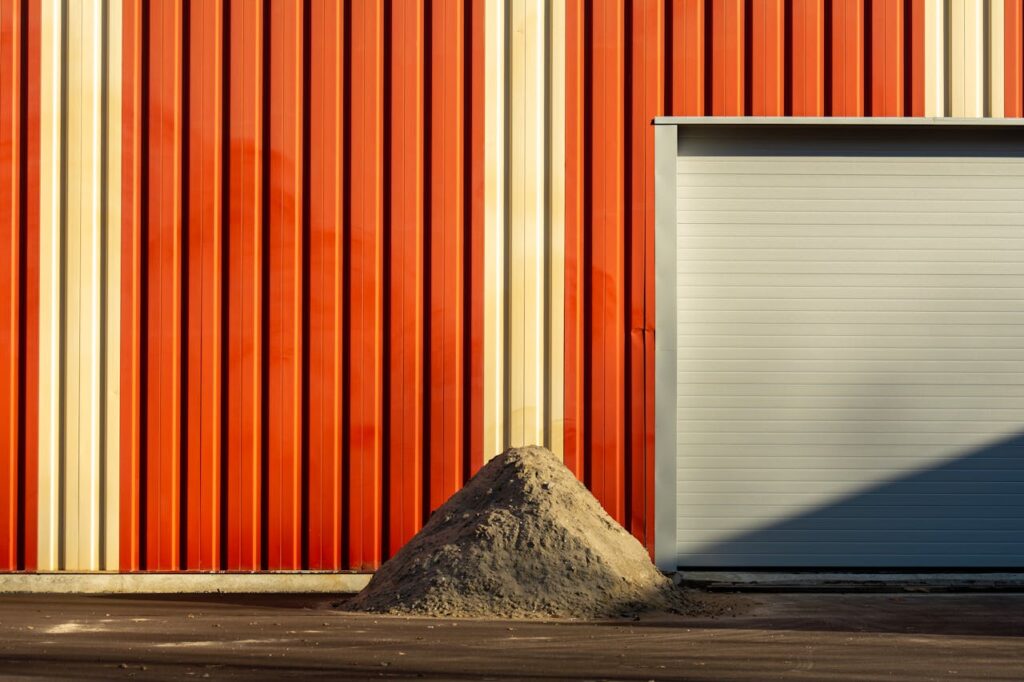 Contemporary building with red metal facade and garage door, highlighting industrial design.